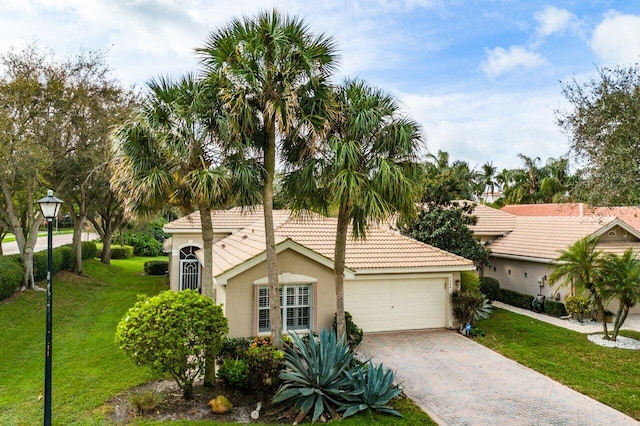 mediterranean / spanish home featuring an attached garage, a tiled roof, decorative driveway, stucco siding, and a front yard