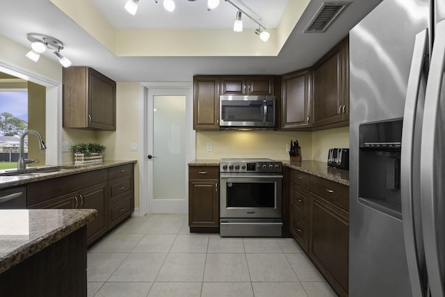 kitchen with stainless steel appliances, a raised ceiling, visible vents, a sink, and dark brown cabinets