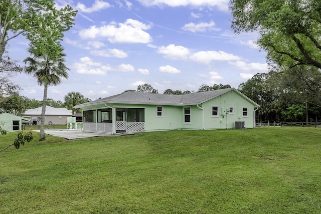 back of property featuring central air condition unit, a sunroom, fence, and a yard