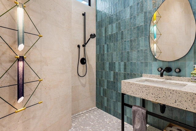 bathroom with a tile shower, a sink, and tile walls