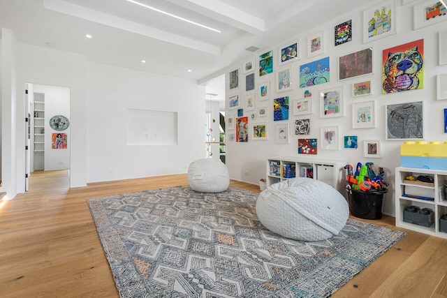 recreation room with beamed ceiling and wood finished floors