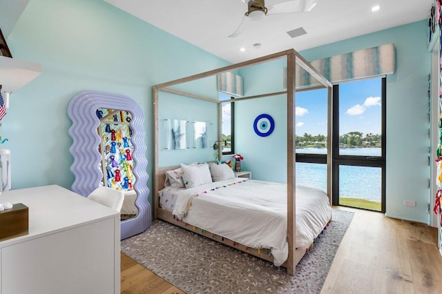 bedroom with light wood-type flooring, a water view, ceiling fan, and recessed lighting