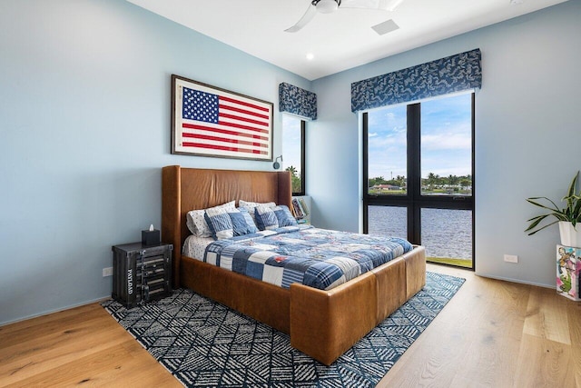 bedroom with ceiling fan, wood finished floors, and baseboards