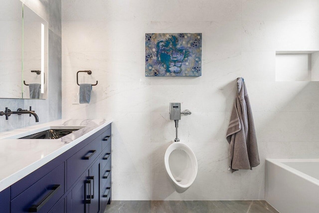 bathroom featuring a bathtub, vanity, and tile walls