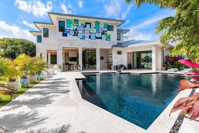 back of property with a patio area, an outdoor pool, outdoor dry bar, and stucco siding