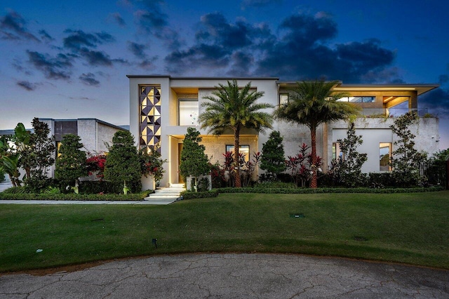 modern home with a front yard and stucco siding