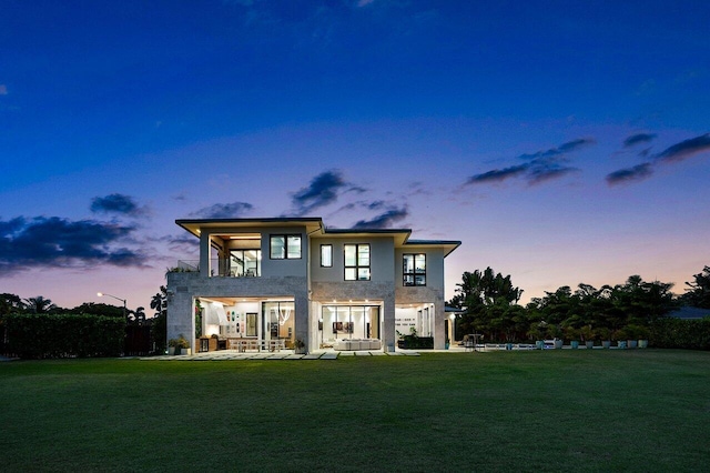 rear view of property featuring a patio, a lawn, a balcony, and stucco siding