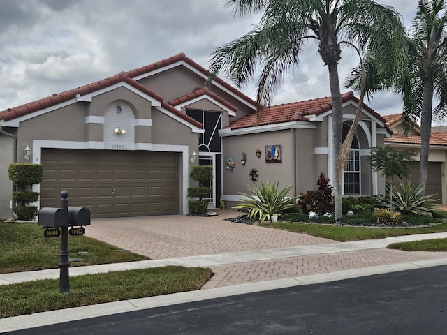 mediterranean / spanish home featuring decorative driveway, a tile roof, an attached garage, and stucco siding