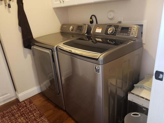 laundry room with dark wood-style floors, separate washer and dryer, cabinet space, and baseboards