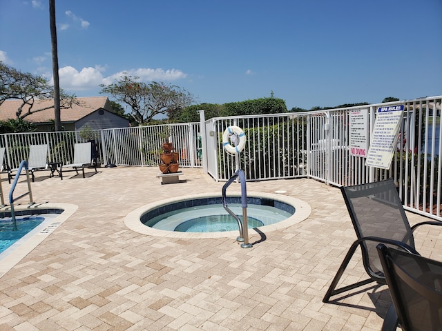 view of swimming pool featuring fence and a hot tub