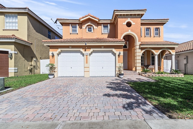 mediterranean / spanish home with a front lawn, decorative driveway, an attached garage, and stucco siding