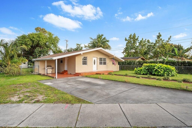 ranch-style house with concrete driveway, fence, a front lawn, and stucco siding