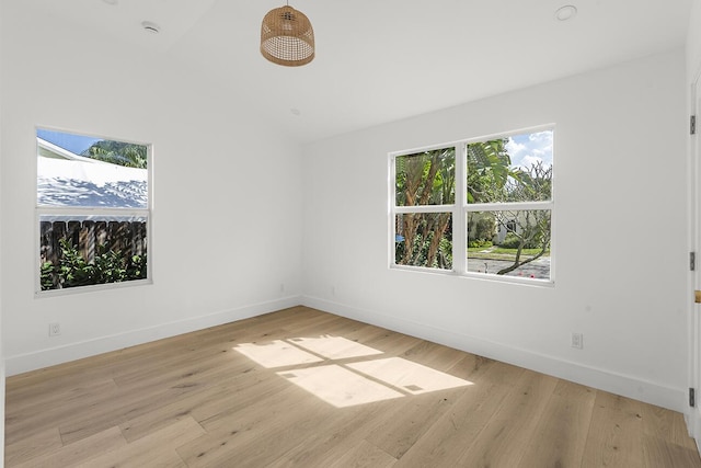 spare room with light wood-style flooring, lofted ceiling, and baseboards