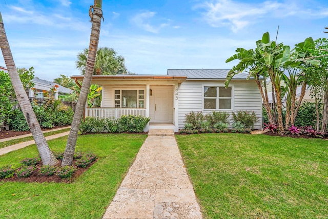 view of front of property featuring metal roof, a front lawn, and covered porch