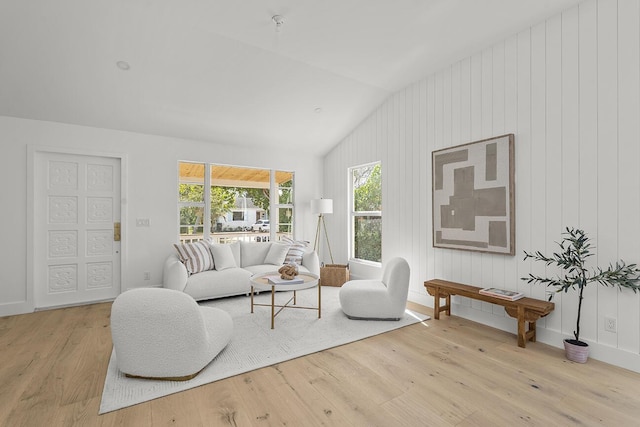 living room with vaulted ceiling, baseboards, and light wood-style flooring