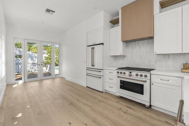 kitchen featuring wall chimney exhaust hood, french doors, tasteful backsplash, white appliances, and light countertops