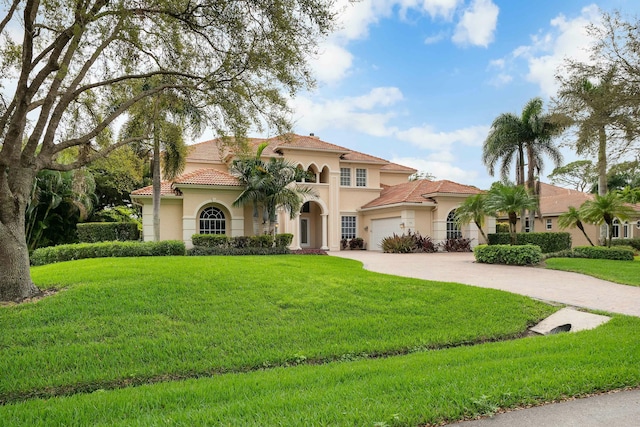 mediterranean / spanish-style home with a garage, decorative driveway, a front lawn, and stucco siding