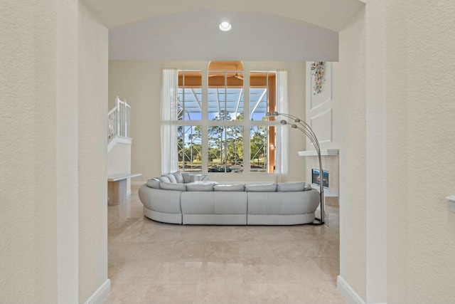 living room featuring baseboards, lofted ceiling, and a textured wall