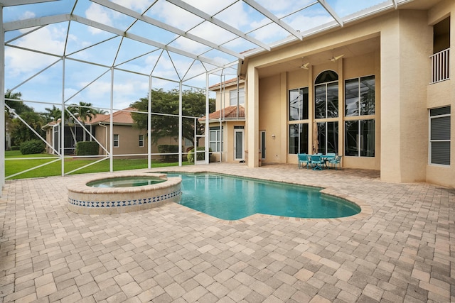 view of swimming pool featuring a patio, glass enclosure, ceiling fan, a yard, and a pool with connected hot tub