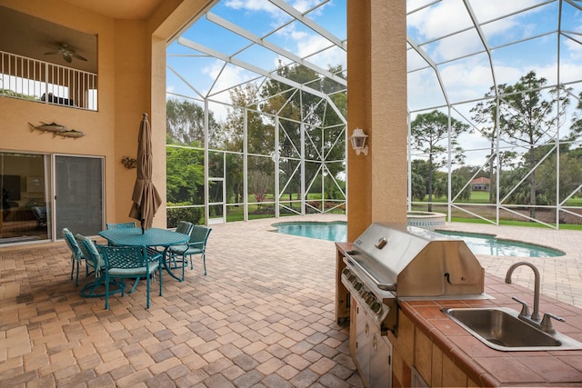 view of patio featuring area for grilling, a ceiling fan, glass enclosure, a sink, and an outdoor pool