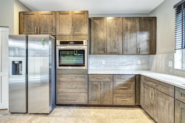 kitchen featuring appliances with stainless steel finishes, backsplash, and light stone counters