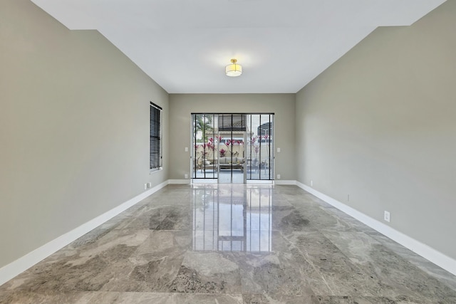 unfurnished room featuring marble finish floor and baseboards