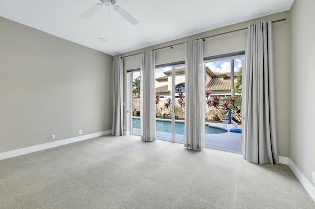 spare room featuring light speckled floor, a ceiling fan, and baseboards