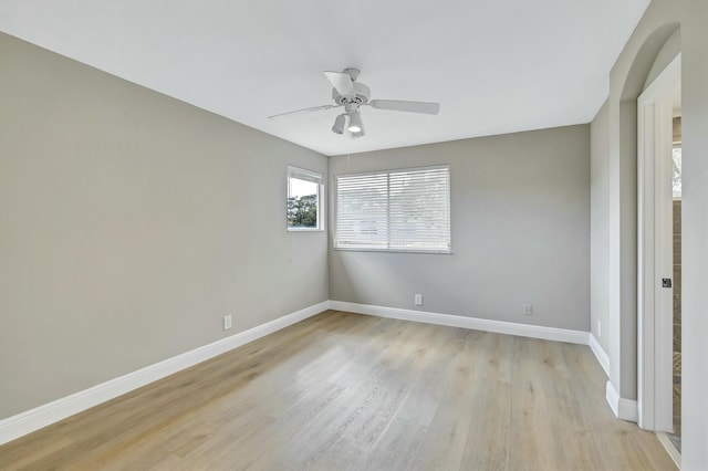 spare room with ceiling fan, light wood finished floors, and baseboards