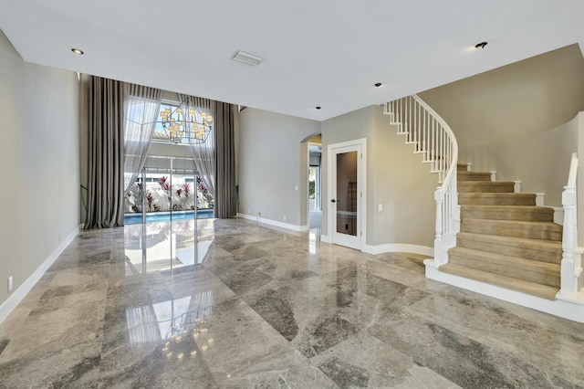 foyer featuring stairs, marble finish floor, arched walkways, and baseboards