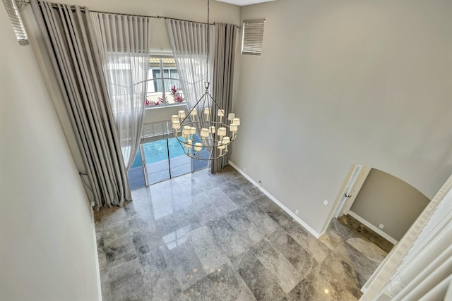 unfurnished dining area with a chandelier and baseboards