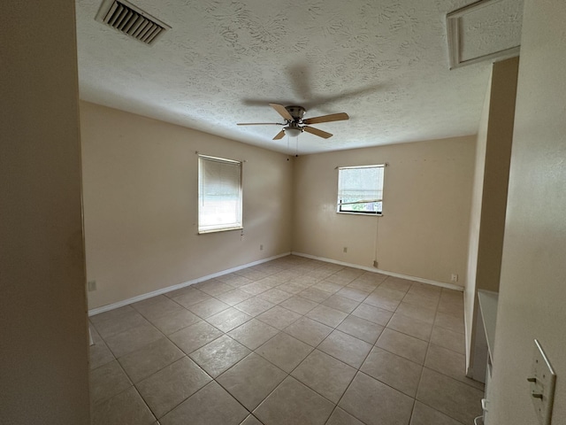 unfurnished room with visible vents, a ceiling fan, light tile patterned flooring, a textured ceiling, and baseboards