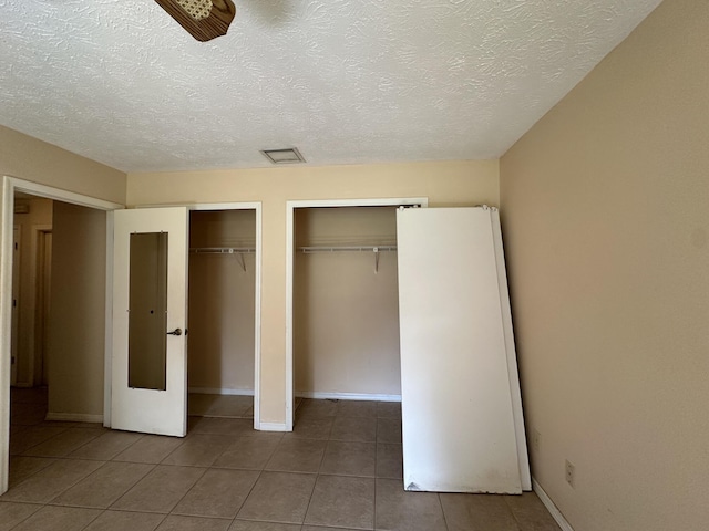 unfurnished bedroom with multiple closets, visible vents, baseboards, and tile patterned floors