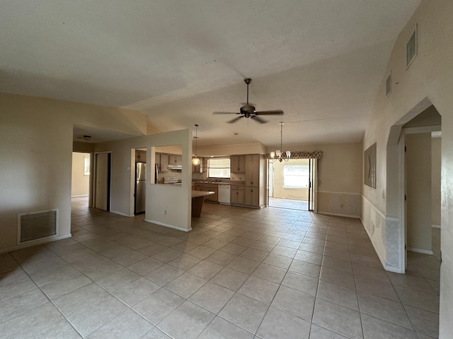 unfurnished living room featuring ceiling fan with notable chandelier, lofted ceiling, visible vents, and light tile patterned floors