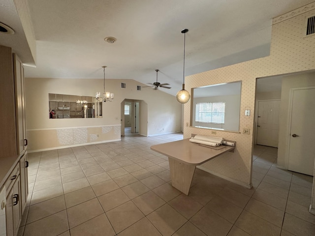 kitchen with wallpapered walls, light tile patterned floors, lofted ceiling, open floor plan, and hanging light fixtures