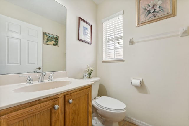 half bathroom with toilet, baseboards, and vanity