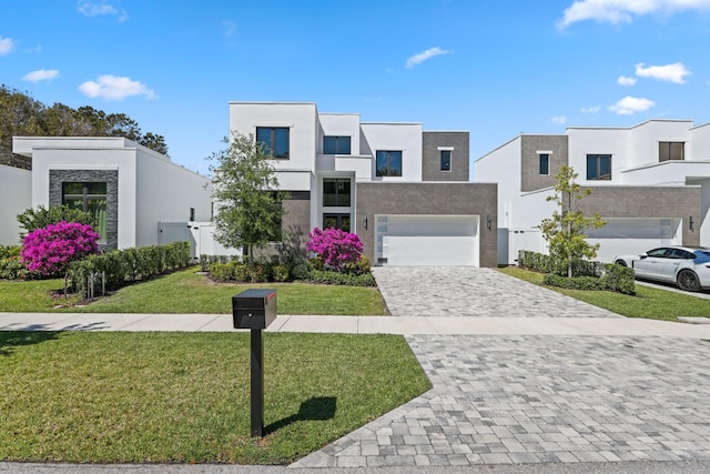 contemporary home with stucco siding, a front lawn, decorative driveway, and a garage