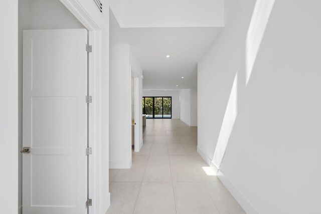 corridor with recessed lighting, light tile patterned floors, and baseboards