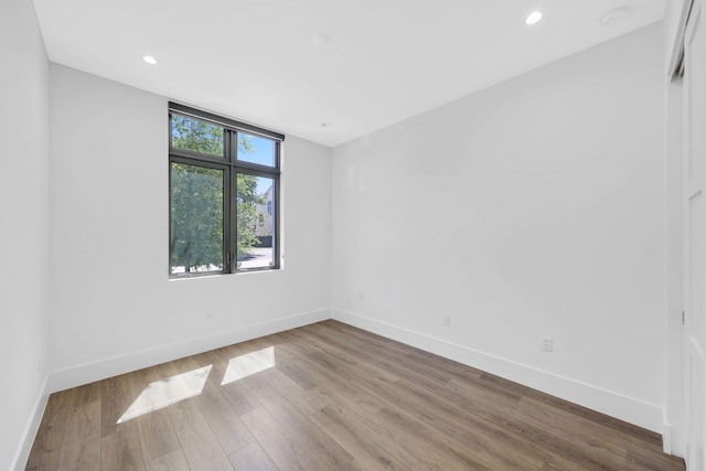 unfurnished room featuring wood finished floors, baseboards, and recessed lighting