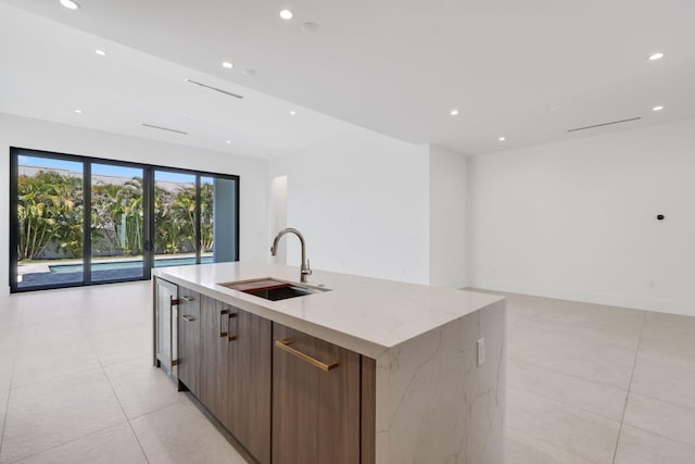 kitchen featuring open floor plan, a kitchen island with sink, a sink, and recessed lighting