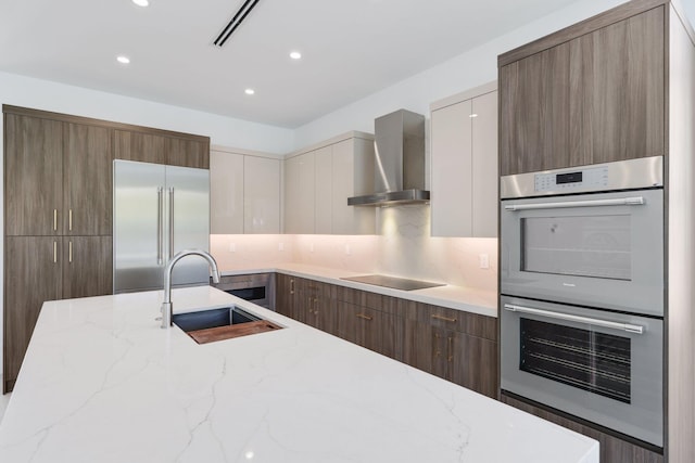 kitchen featuring wall chimney exhaust hood, modern cabinets, and appliances with stainless steel finishes
