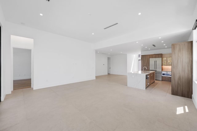 unfurnished living room featuring recessed lighting, visible vents, and a sink