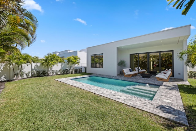 rear view of house featuring stucco siding, a fenced in pool, a fenced backyard, and a lawn