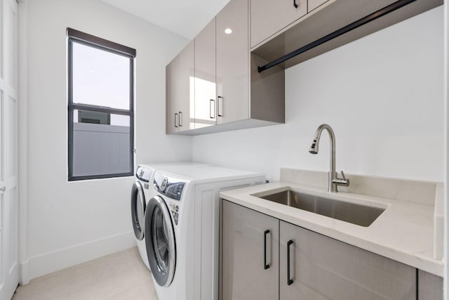 laundry area with light tile patterned floors, baseboards, a sink, cabinet space, and washing machine and dryer