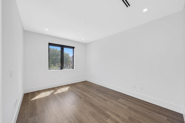 spare room with dark wood-type flooring, visible vents, baseboards, and recessed lighting