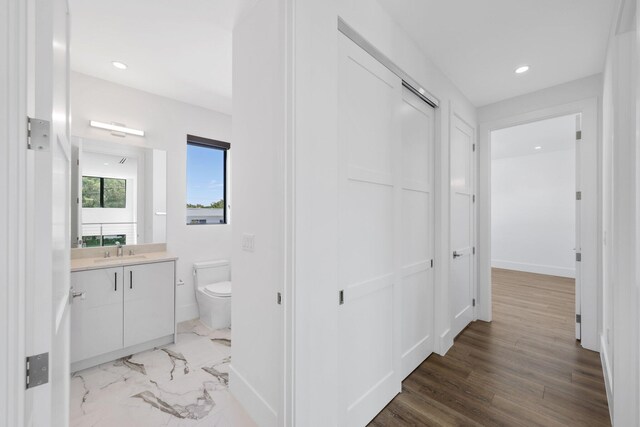 hallway featuring a sink, baseboards, and recessed lighting