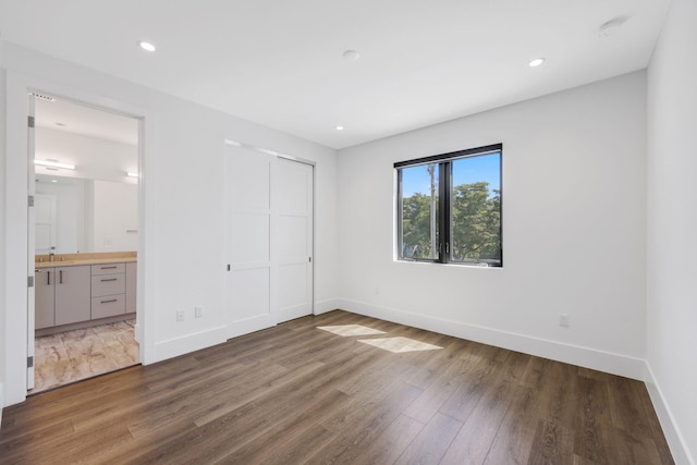 unfurnished bedroom with wood finished floors, baseboards, and a closet