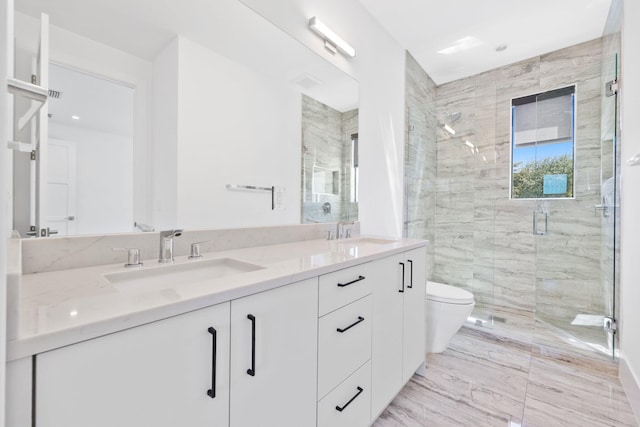 bathroom featuring double vanity, a shower stall, toilet, and a sink
