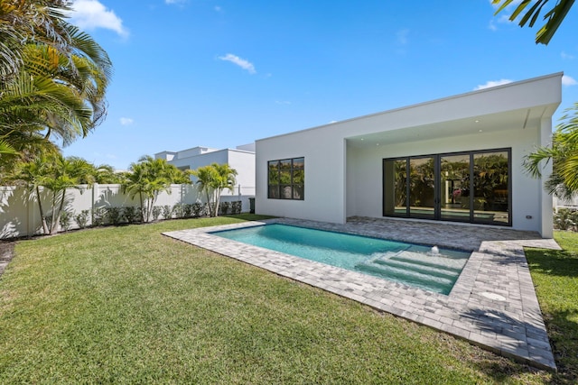 rear view of house featuring a yard, stucco siding, fence private yard, a patio, and a fenced in pool