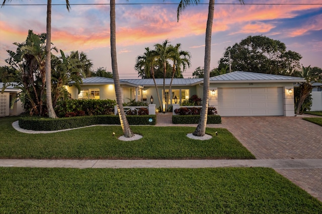 single story home featuring a standing seam roof, stucco siding, decorative driveway, and metal roof