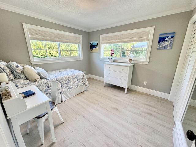 bedroom with light wood-style flooring, a textured ceiling, baseboards, and ornamental molding